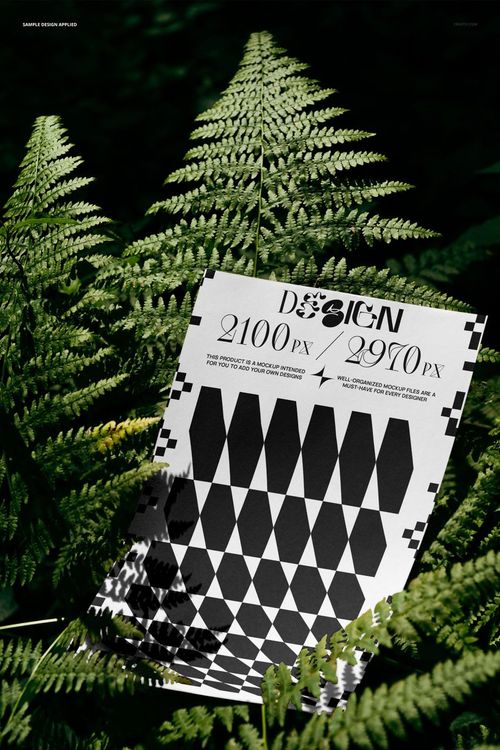 PSD mockup showing a rectangular poster with bold black and white design resting on vibrant fern foliage outdoors.