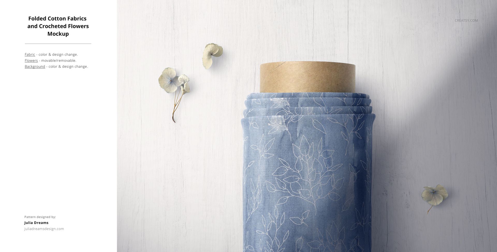 PSD mockup showing folded blue cotton fabric with white floral outlines, placed beside two dried flowers on a pale background.