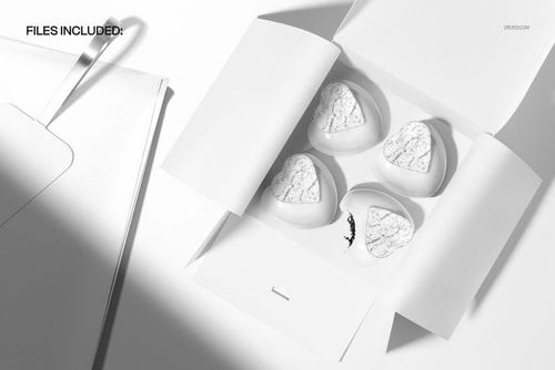 Top view of a white pastry box containing four heart-shaped cakes with marble patterns, shown in a PSD mockup scene.