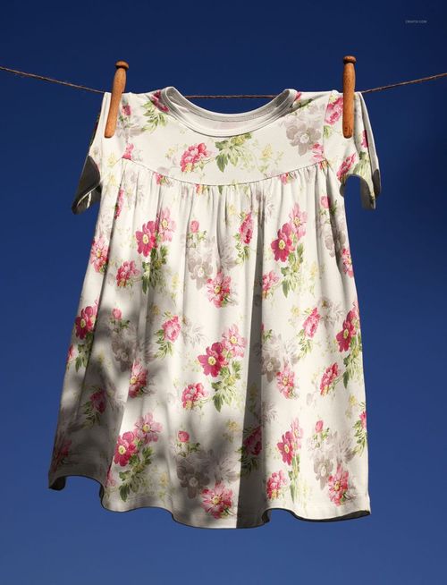 Kids swing dress mockup featuring a floral print, displayed on a line outdoors with wooden clothespins and blue background.