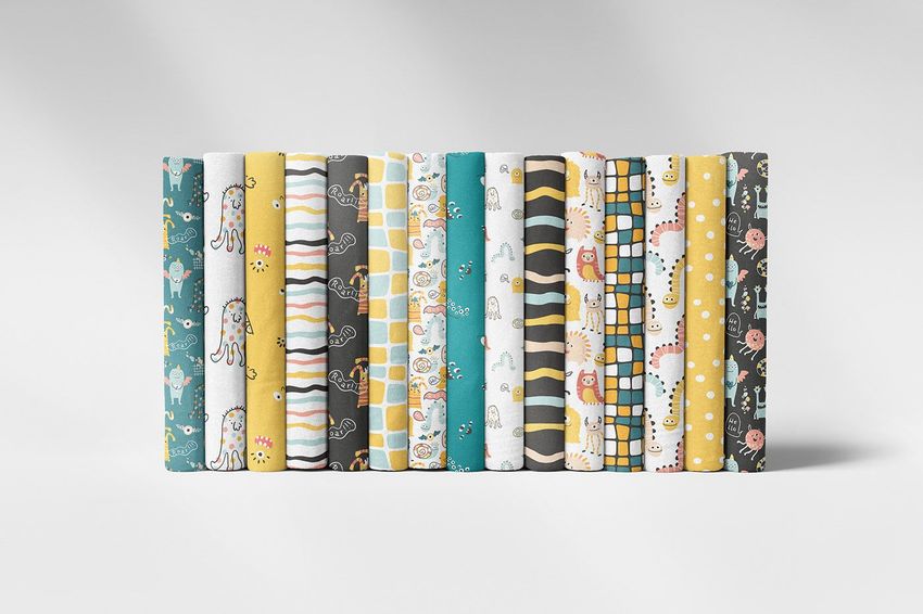 Folded fabrics mockup featuring a row of colorful fabric pieces with playful monster and geometric patterns on a white background.