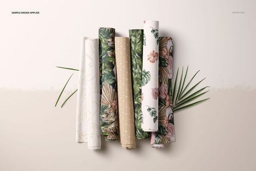PSD mockup showing multiple fabric rolls with various nature-inspired prints, presented on a beige surface with decorative leaves.