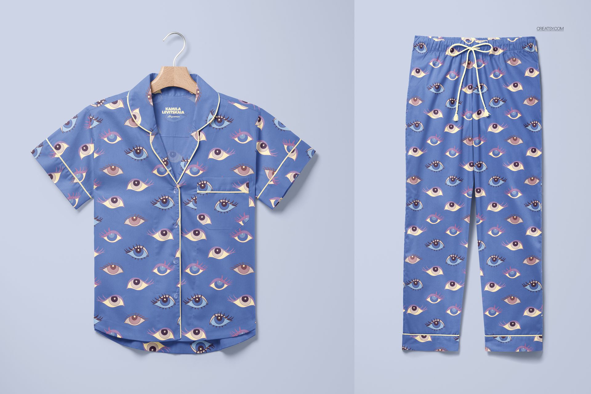 Short-sleeve pajama set mockup featuring blue shirt and pants with eye pattern, shown on a light background.