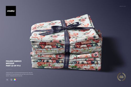Folded fabric mockup featuring colorful floral and flamingo designs, stacked and wrapped with a ribbon on a solid background.