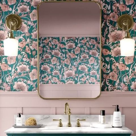 Bathroom mockup featuring a marble countertop with toiletries, gold faucet, and a large mirror reflecting floral wallpaper.