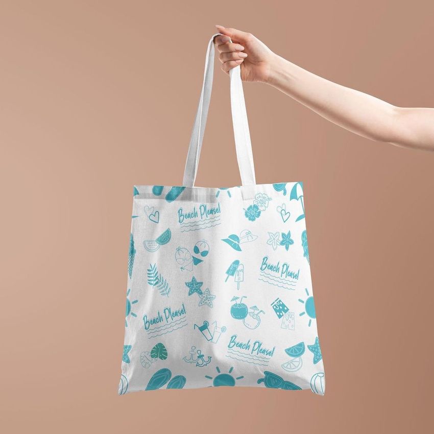 Tote bag mockup featuring a hand holding a white bag with blue beach-themed illustrations and text, set against a beige background.
