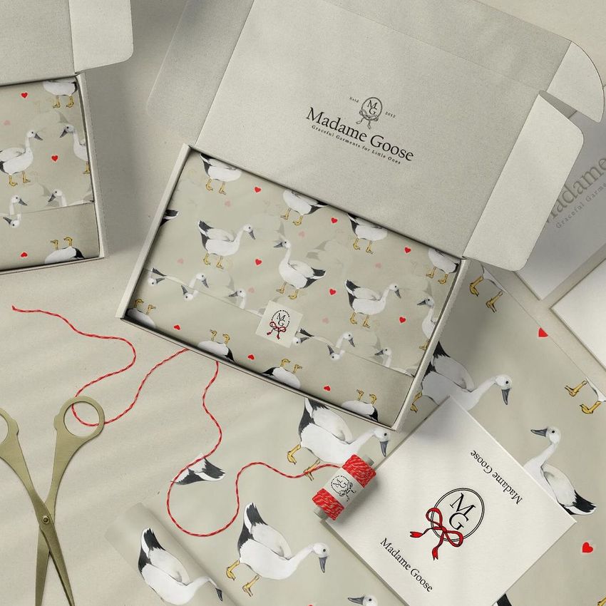 Mailing box mockup featuring a goose-themed design with patterned wrapping paper, open box, and packaging materials on a neutral surface.