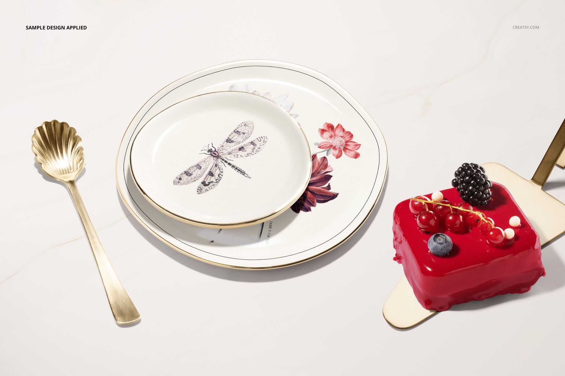 PSD mockup featuring layered plates with botanical and insect motifs, gold utensils, and a dessert on white background.