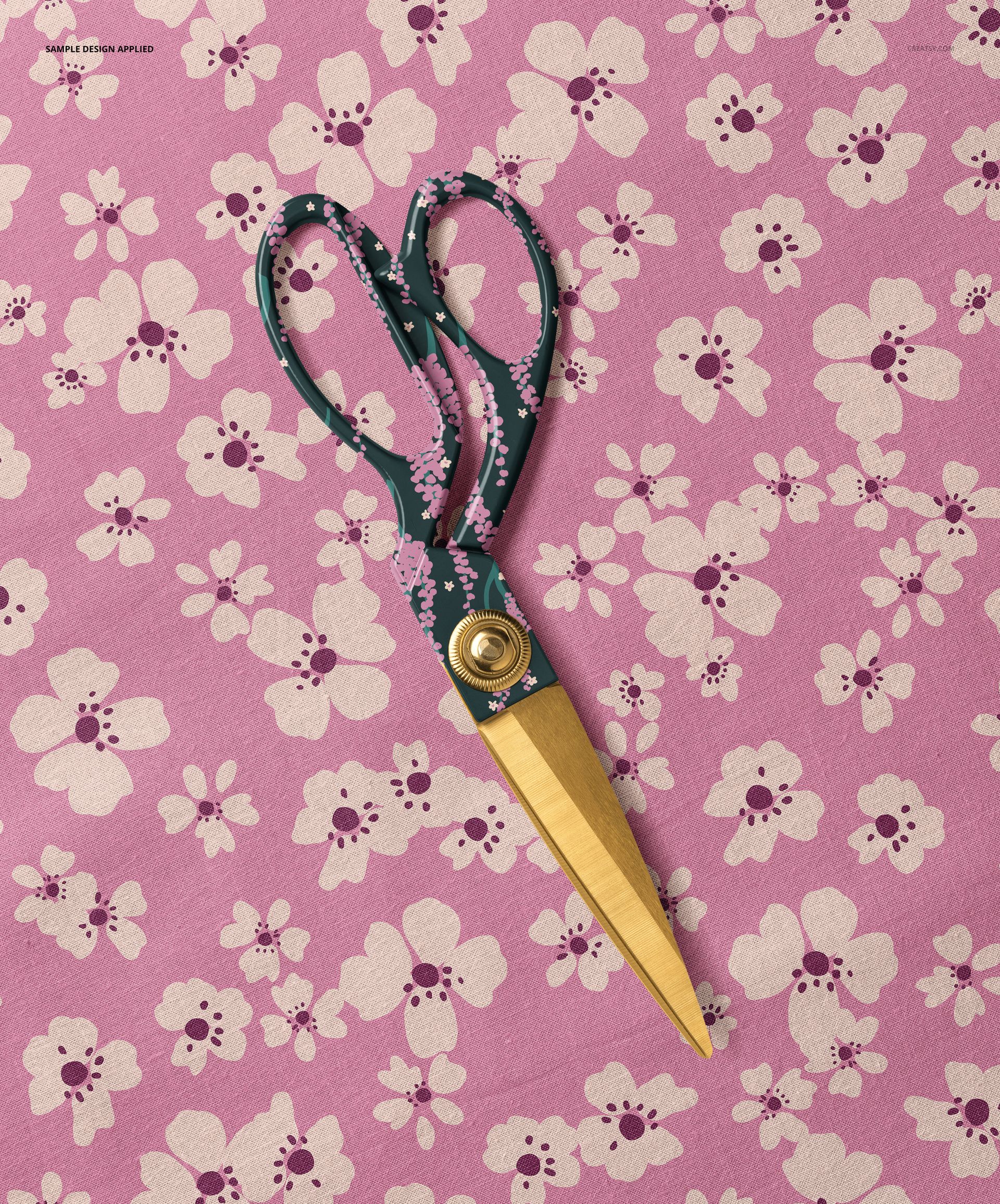 Top view of patterned scissors placed on pink cotton fabric with white floral motifs, shown in a PSD mockup scene.