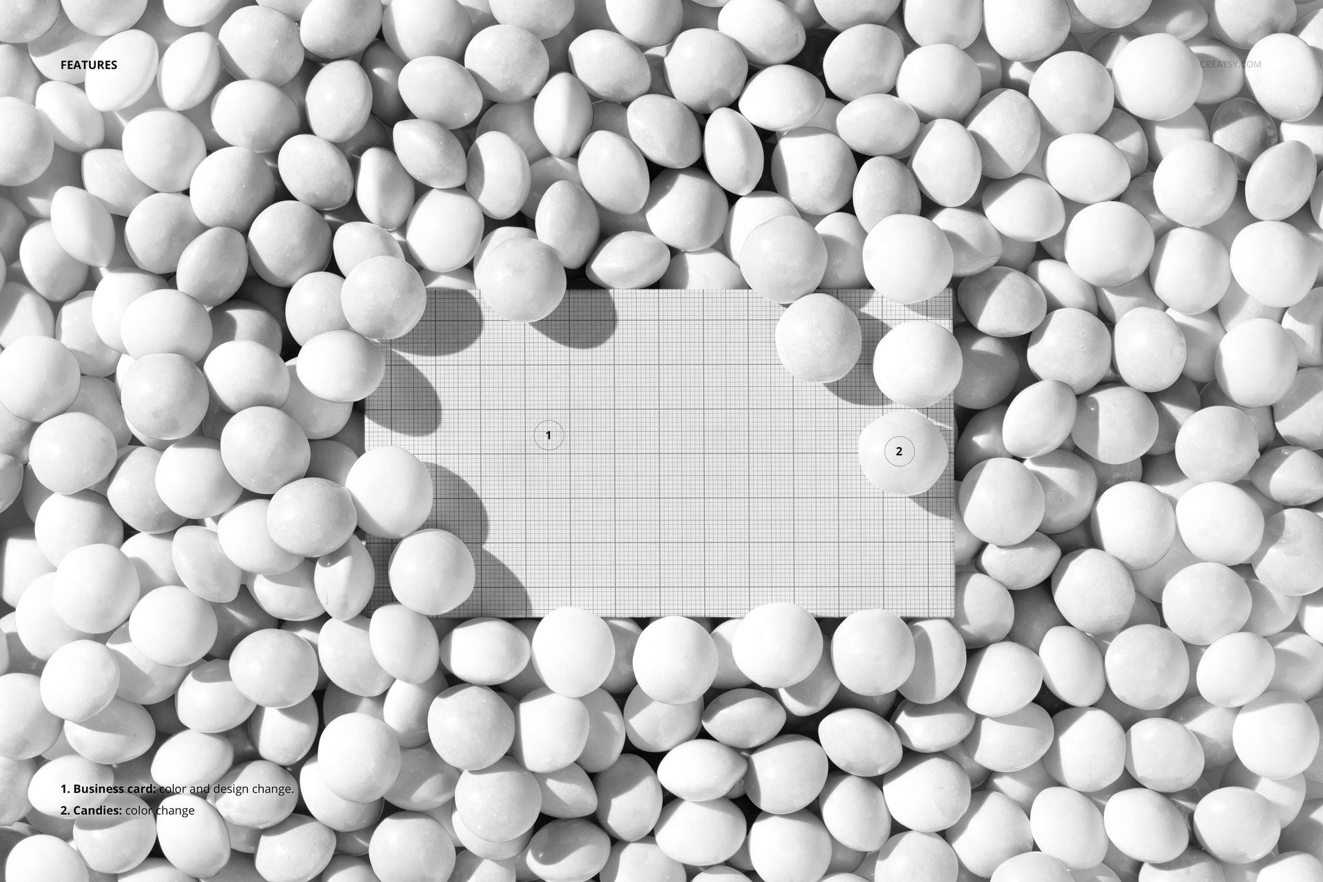 Rectangular business card mockup placed in a pit filled with round candy balls, top view, grayscale color scheme.