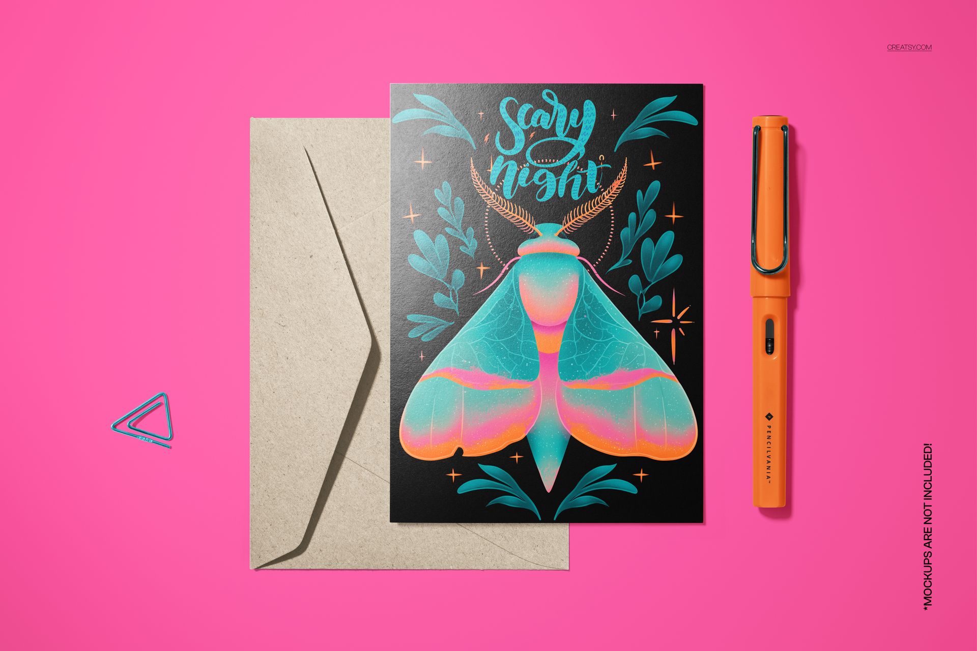 Vintage Halloween card mockup with colorful moth design, envelope, and orange pen arranged on a bright pink surface.