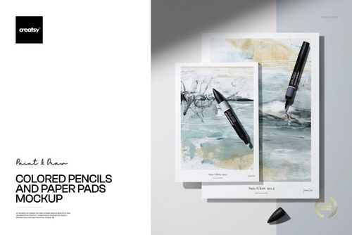 PSD mockup showing colored pencils placed on top of paper pads with abstract designs, viewed from above.
