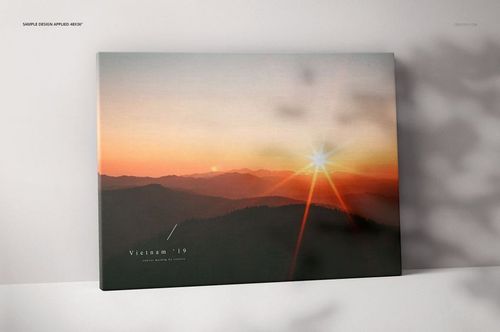 Front view of a thick canvas print mockup with a sunset landscape design, resting against a light wall with soft shadows.