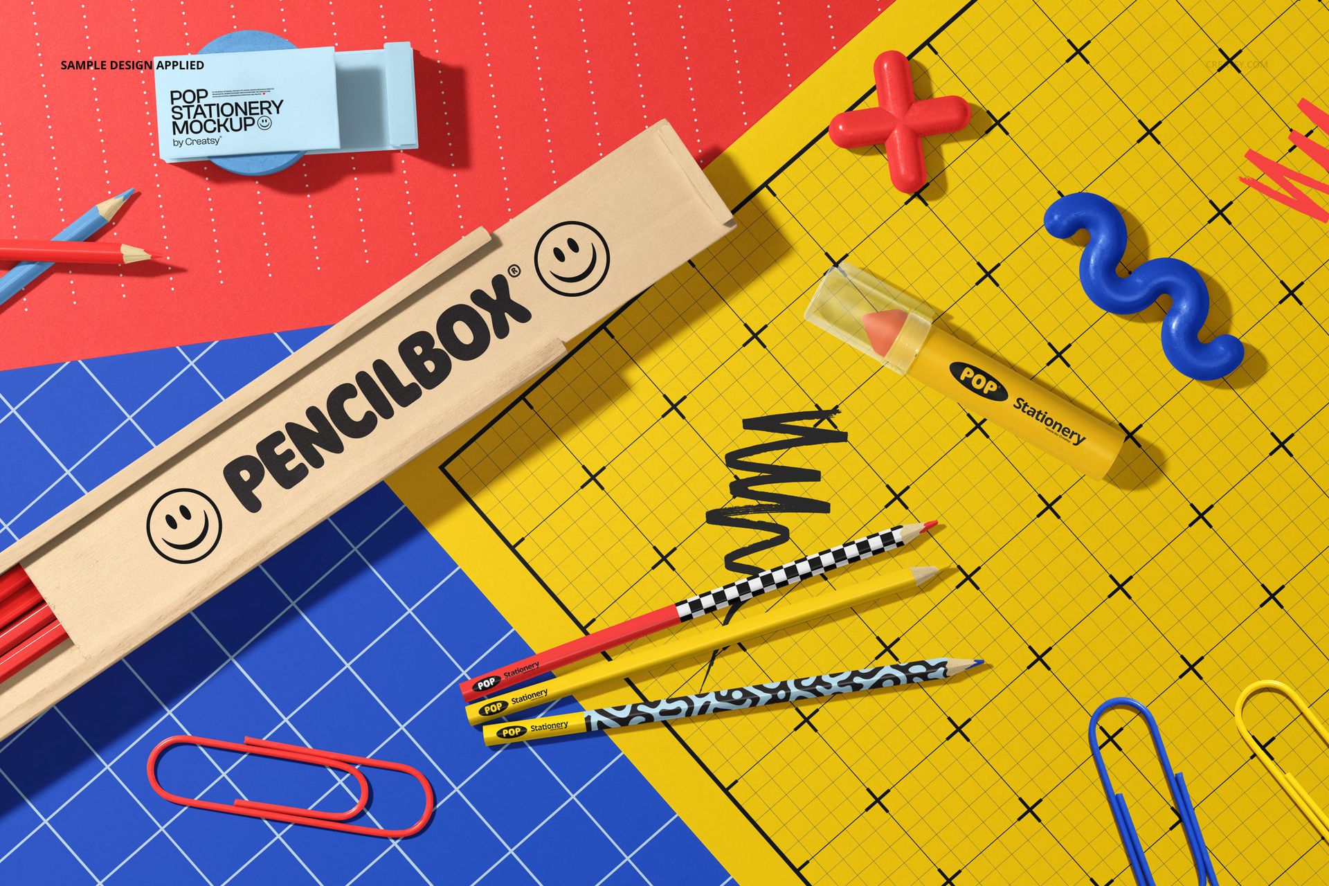 Stationery mockup showing a wooden pencil box, assorted pencils, and vibrant paper sheets with geometric patterns.