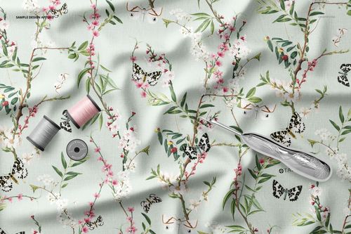 Creased fabric mockup with a floral and butterfly pattern, sewing thread spools, and a seam ripper on a light background.