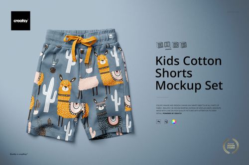 Kids cotton shorts mockup featuring playful llamas and cacti in orange and white on a blue-gray fabric, top-down angle.