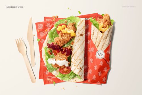 Top view of two tortillas with fried chicken, lettuce, and sauces on red patterned food safe paper mockup.