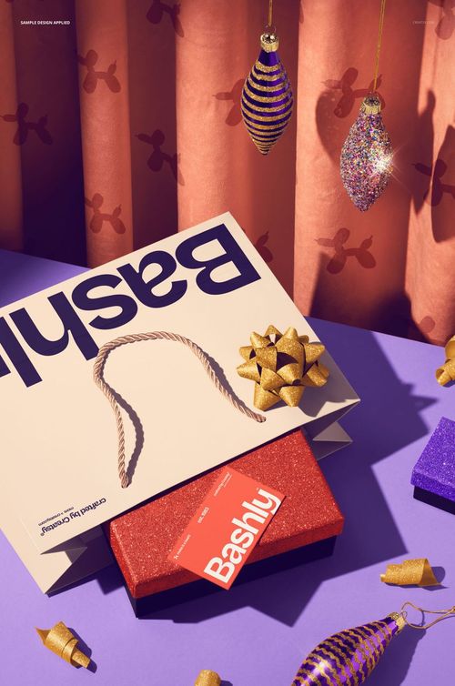Front view of a mockup featuring a beige gift bag, red glitter box, and business card with gold ribbon accents.