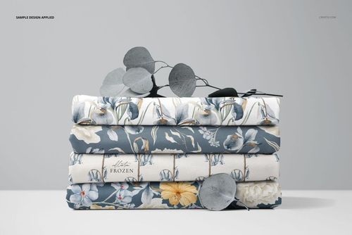 PSD mockup showing a neat pile of floral jersey fabrics, with eucalyptus branches placed on top for decoration.