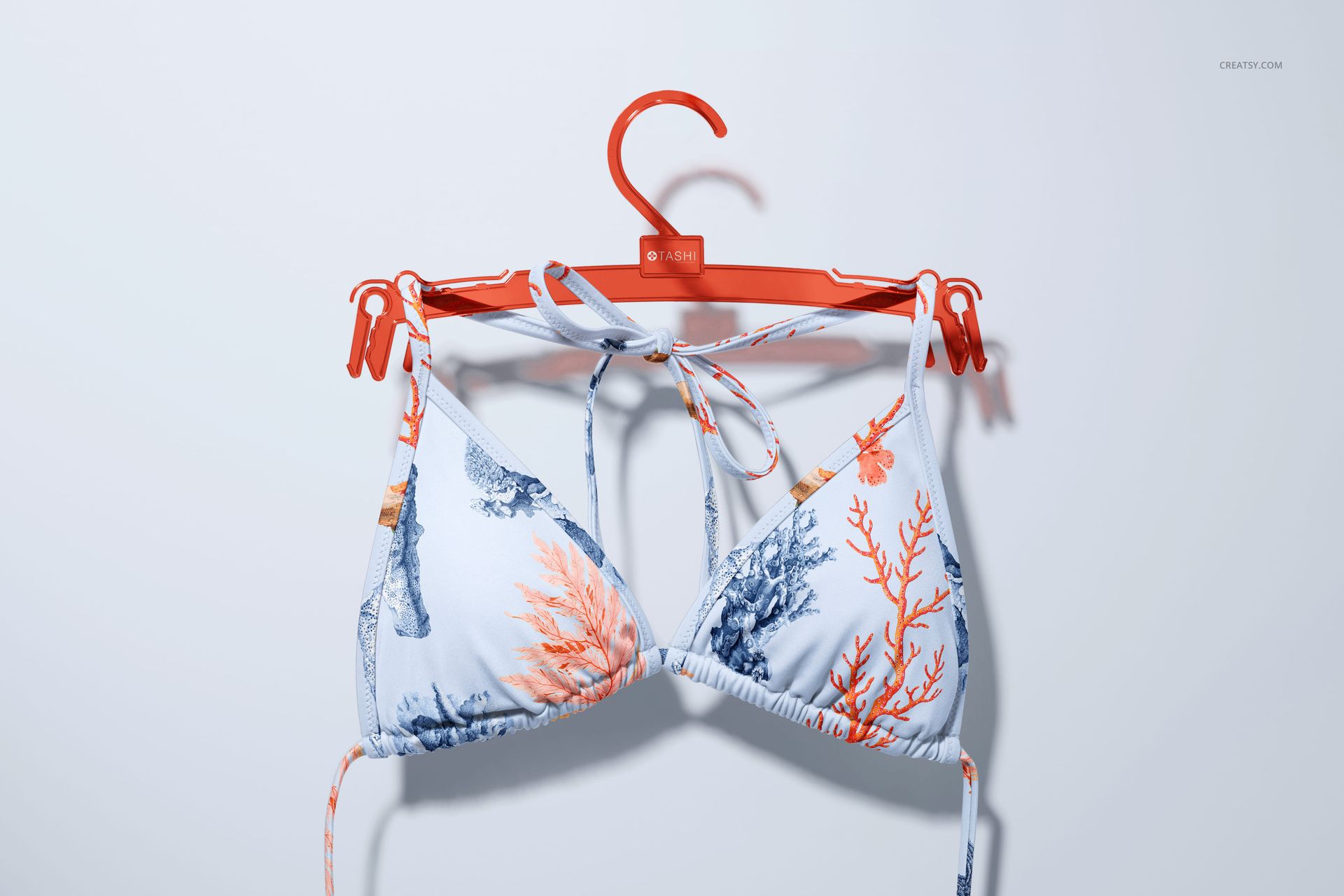 Bikini top mockup featuring a white base with orange and blue marine patterns, displayed on a red hanger.