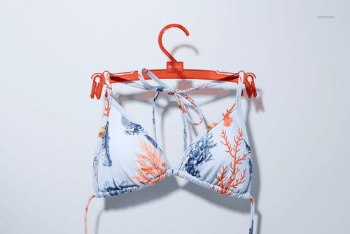 Bikini top mockup featuring a white base with orange and blue marine patterns, displayed on a red hanger.