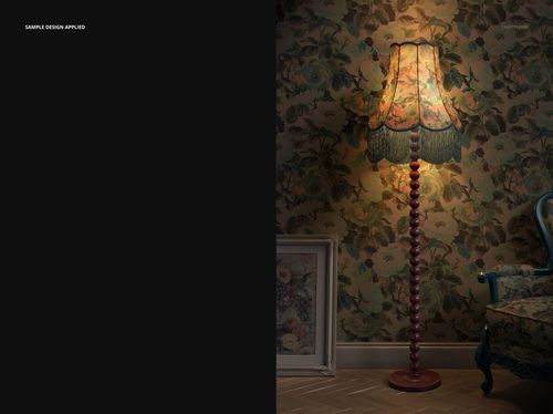 Tall fringed velvet lampshade with floral pattern, glowing warmly in a vintage living room with floral wallpaper.