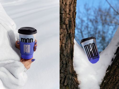PSD mockup of a paper cup with a blue sleeve and black lid, held in a snowy setting and placed on a tree.