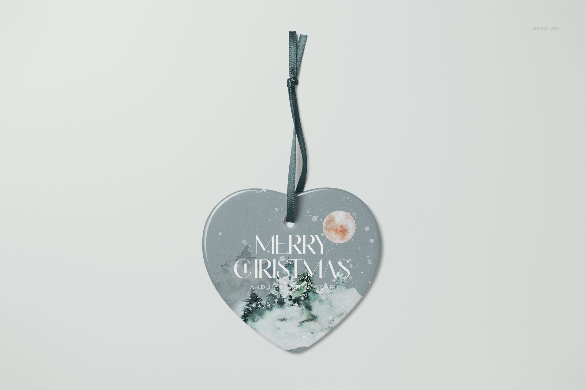 Heart-shaped ceramic Christmas ornament mockup with snowy pine trees and moon design, front view on white background.