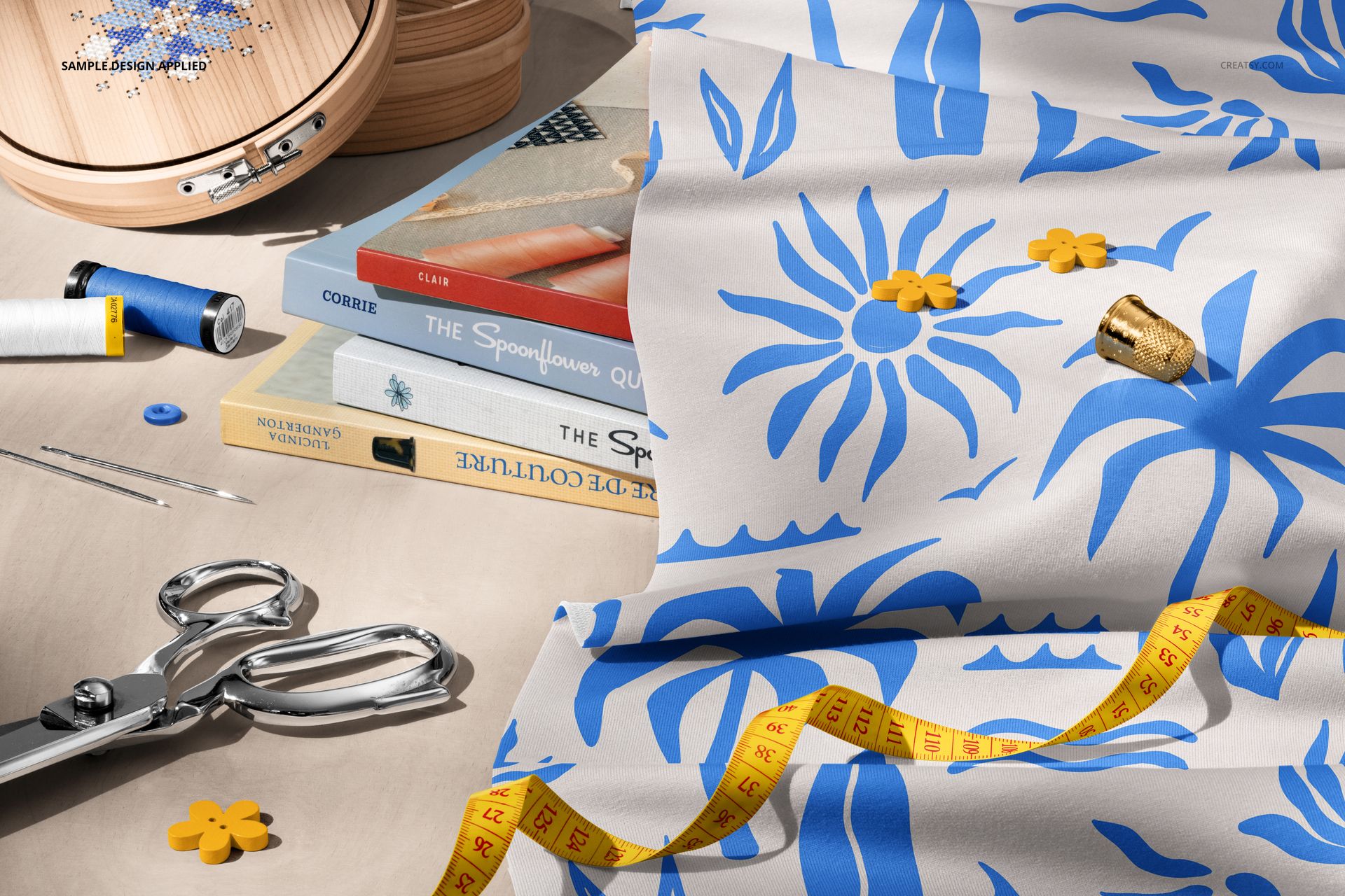 PSD mockup of a creative sewing workspace with blue and white jersey fabric, spools of thread, and crafting tools.