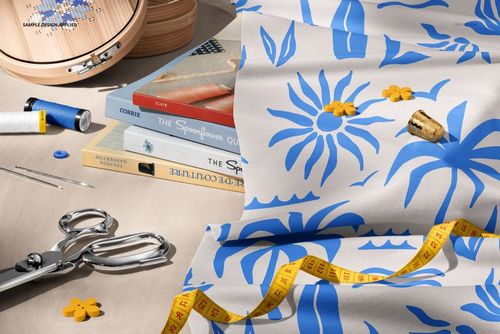 PSD mockup of a creative sewing workspace with blue and white jersey fabric, spools of thread, and crafting tools.