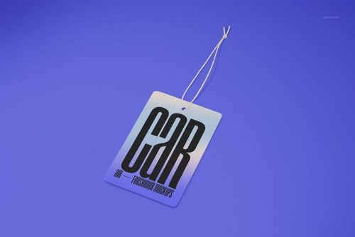 Car air freshener mockup showing a rectangular tag with gradient tones and large black lettering, angled on blue.
