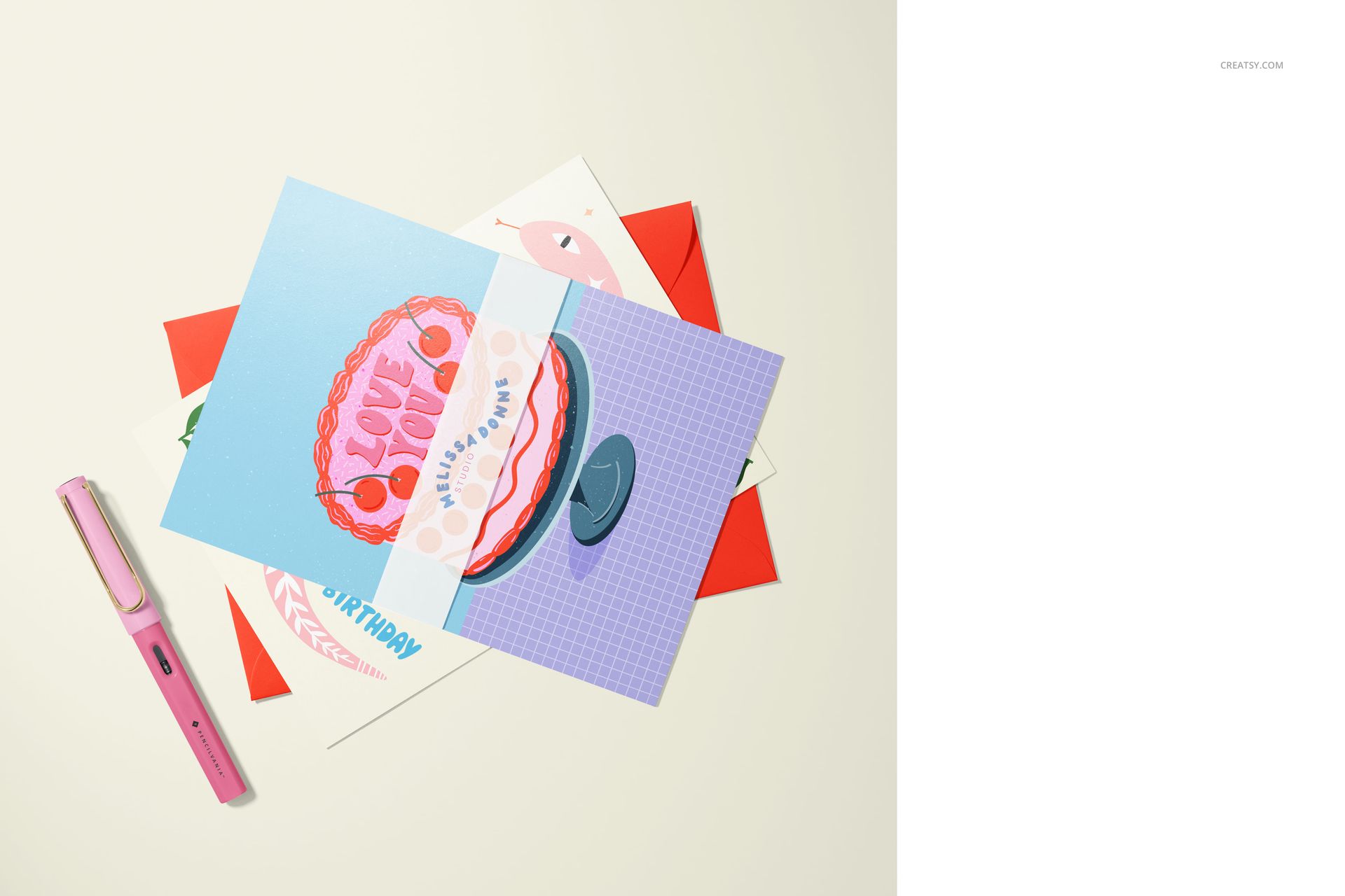 A5 cards mockup featuring several greeting cards with vibrant artwork, arranged with a pink pen on a pale background.