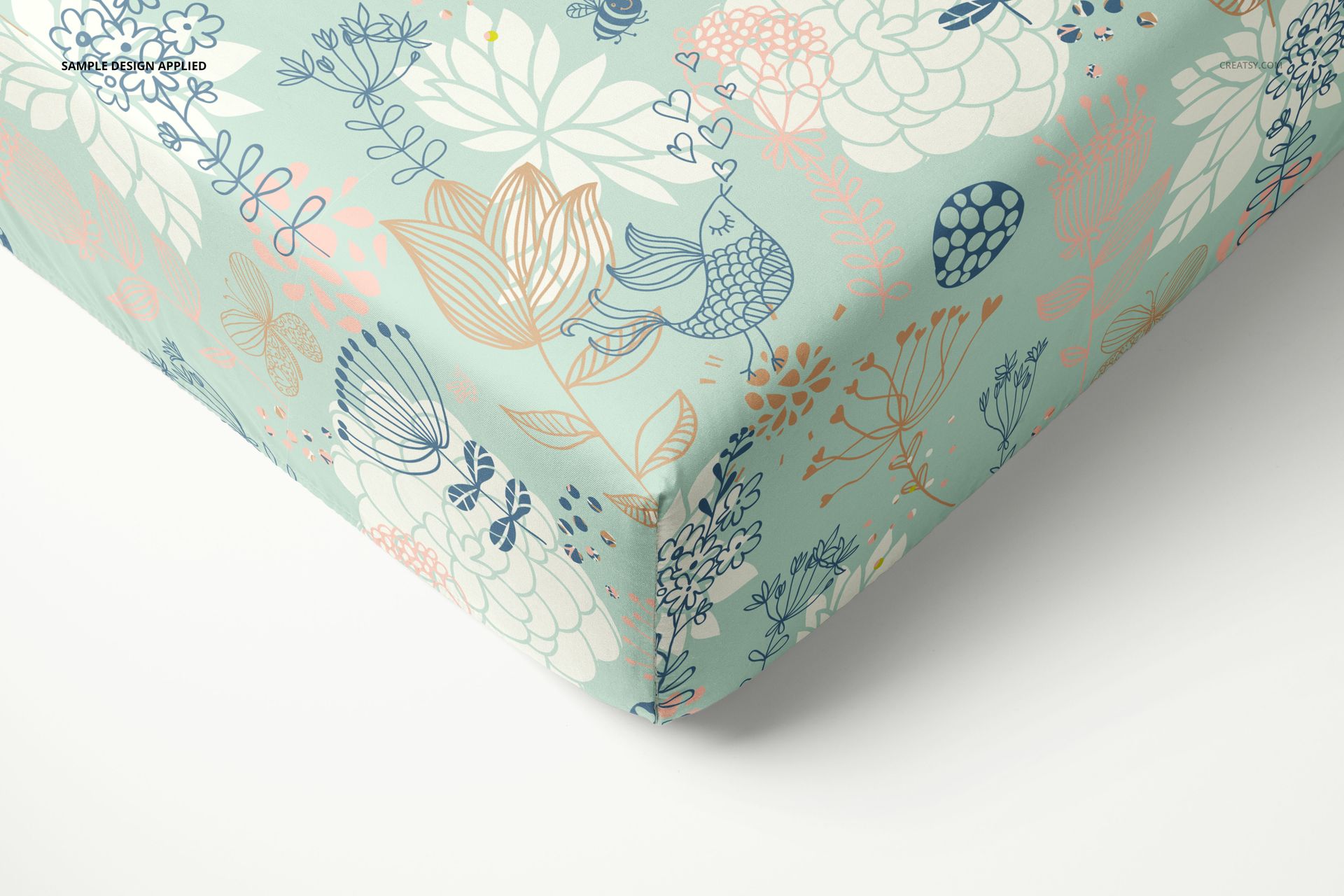 PSD mockup of a crib sheet featuring soft blue, pink, and beige botanical designs, displayed in a close-up perspective.