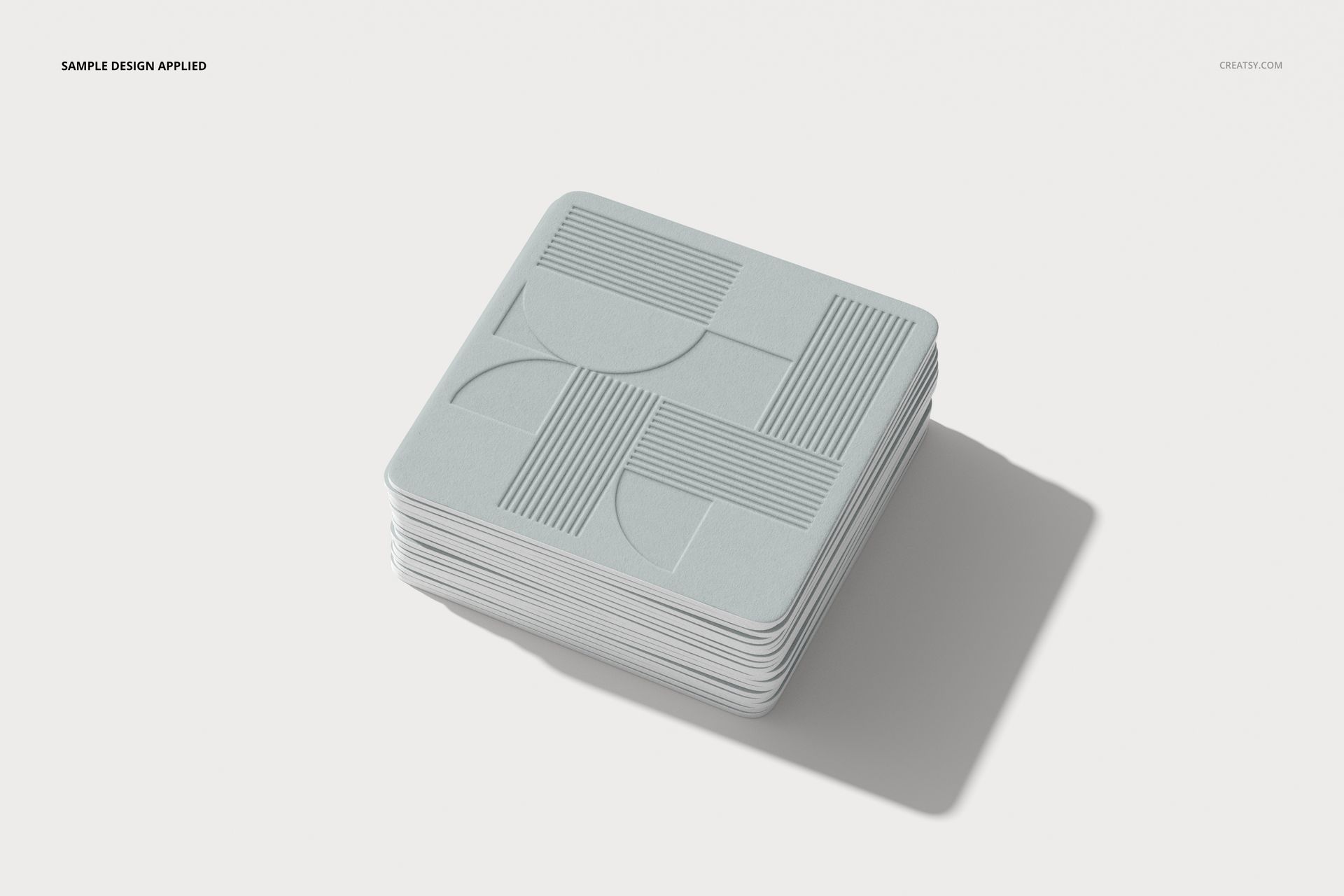 PSD mockup of square coasters with light gray geometric artwork, displayed on a clean, white surface.