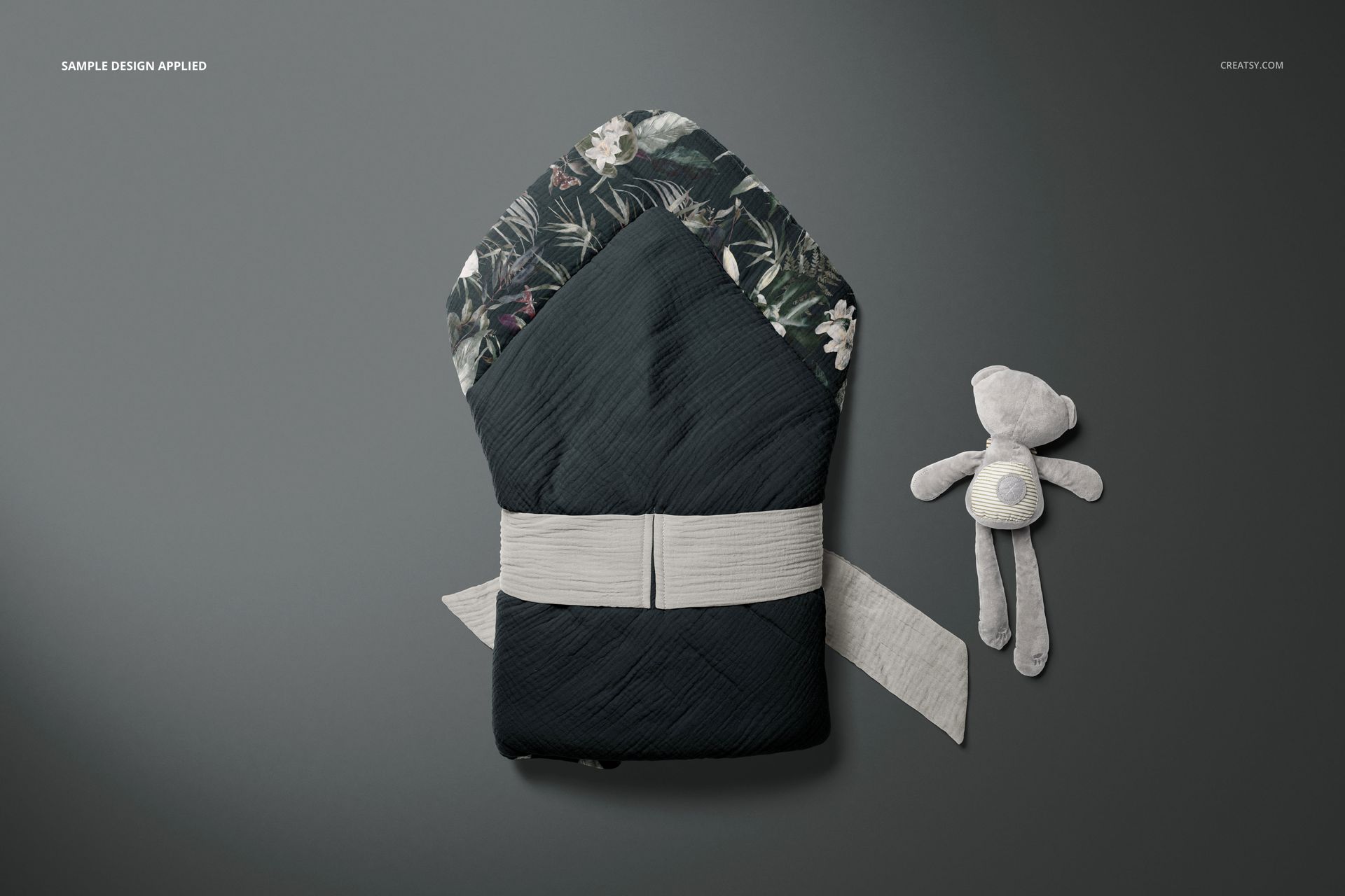 Top view of a muslin baby wrap mockup featuring a dark exterior, floral pattern inside, and a light belt accent.