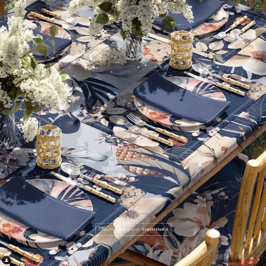 Tablecloth napkins placemat mockup showing a garden table set with floral-patterned linens, navy napkins, and white flowers.