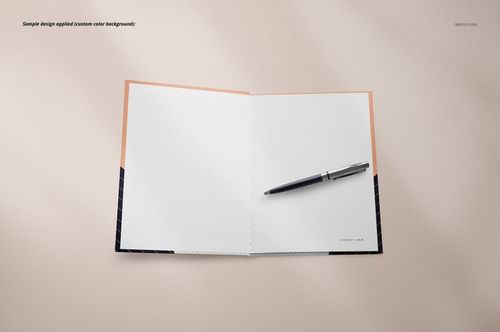 Top view of an open notebook mockup with plain white pages and a pen placed on the right side, on a beige background.
