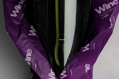 Wine bottle wrapped in purple tissue paper with white text, viewed from above showing partial bottle and paper folds.