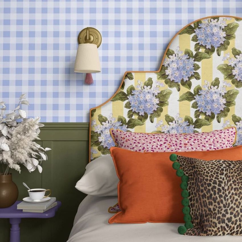 Bedroom mockup featuring patterned pillows, a floral headboard, and blue checkered wallpaper in a cozy setting.