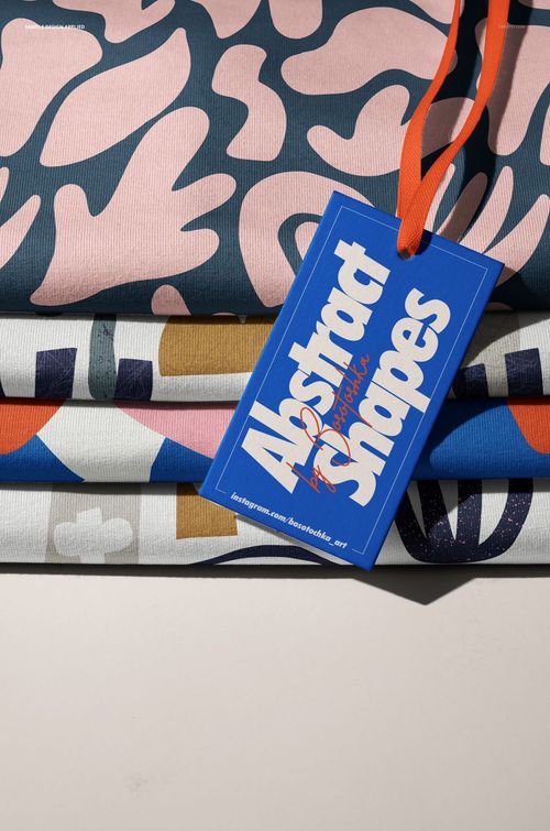 Front perspective of stacked jersey fabric mockup featuring colorful patterns and a blue tag reading 'Abstract Shapes'.