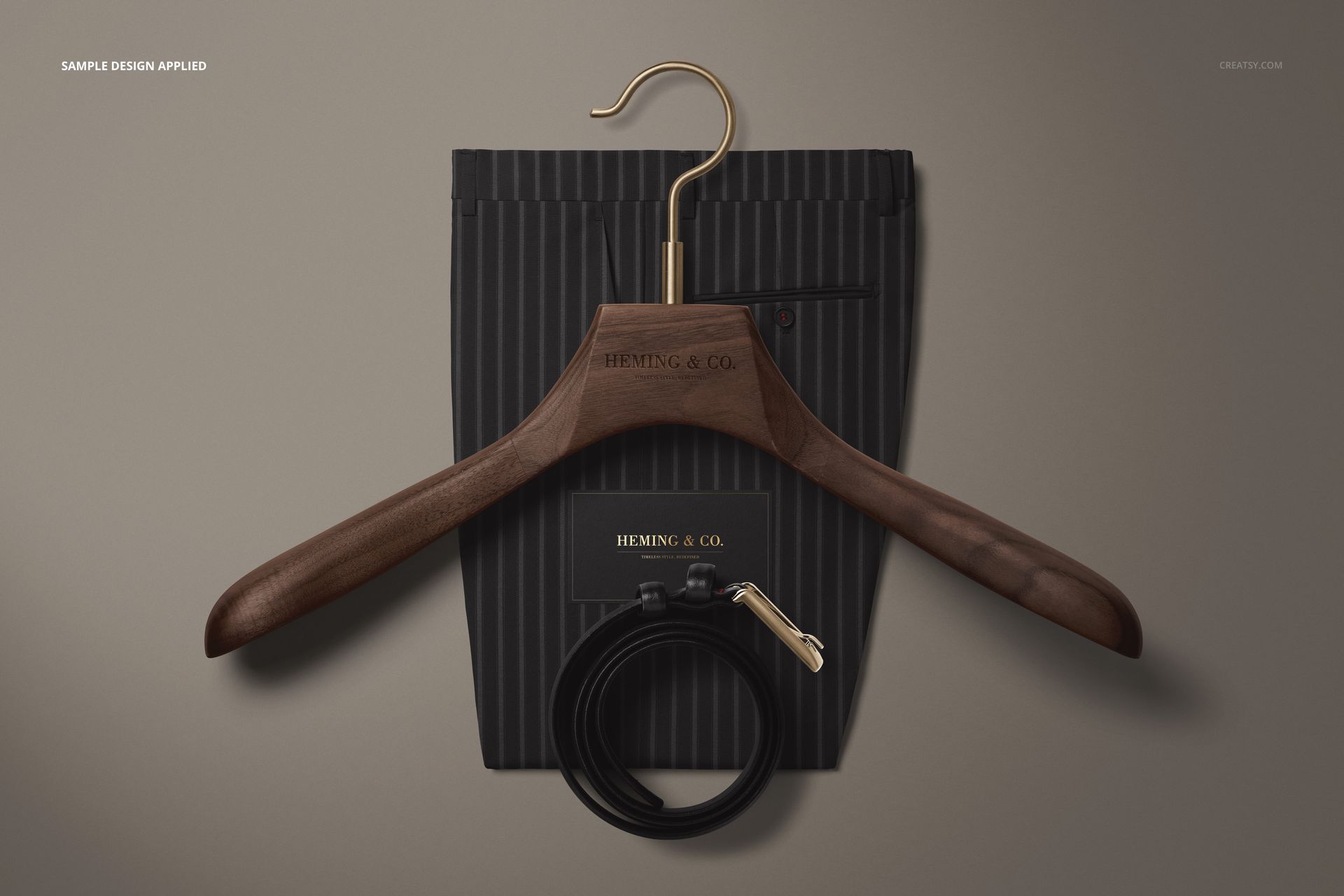 PSD mockup featuring adult men’s pinstriped trousers, wooden hanger with gold hook, card, and rolled leather belt.