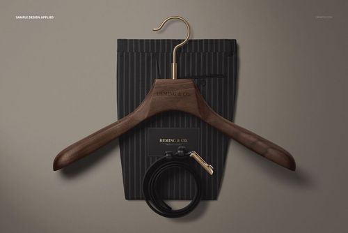 PSD mockup featuring adult men’s pinstriped trousers, wooden hanger with gold hook, card, and rolled leather belt.