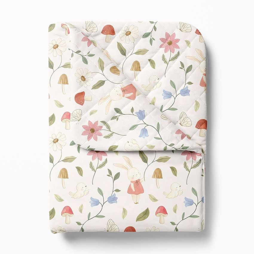 Double-sided baby bedding set mockup featuring a folded quilt with a whimsical bunny and floral pattern on a white background.