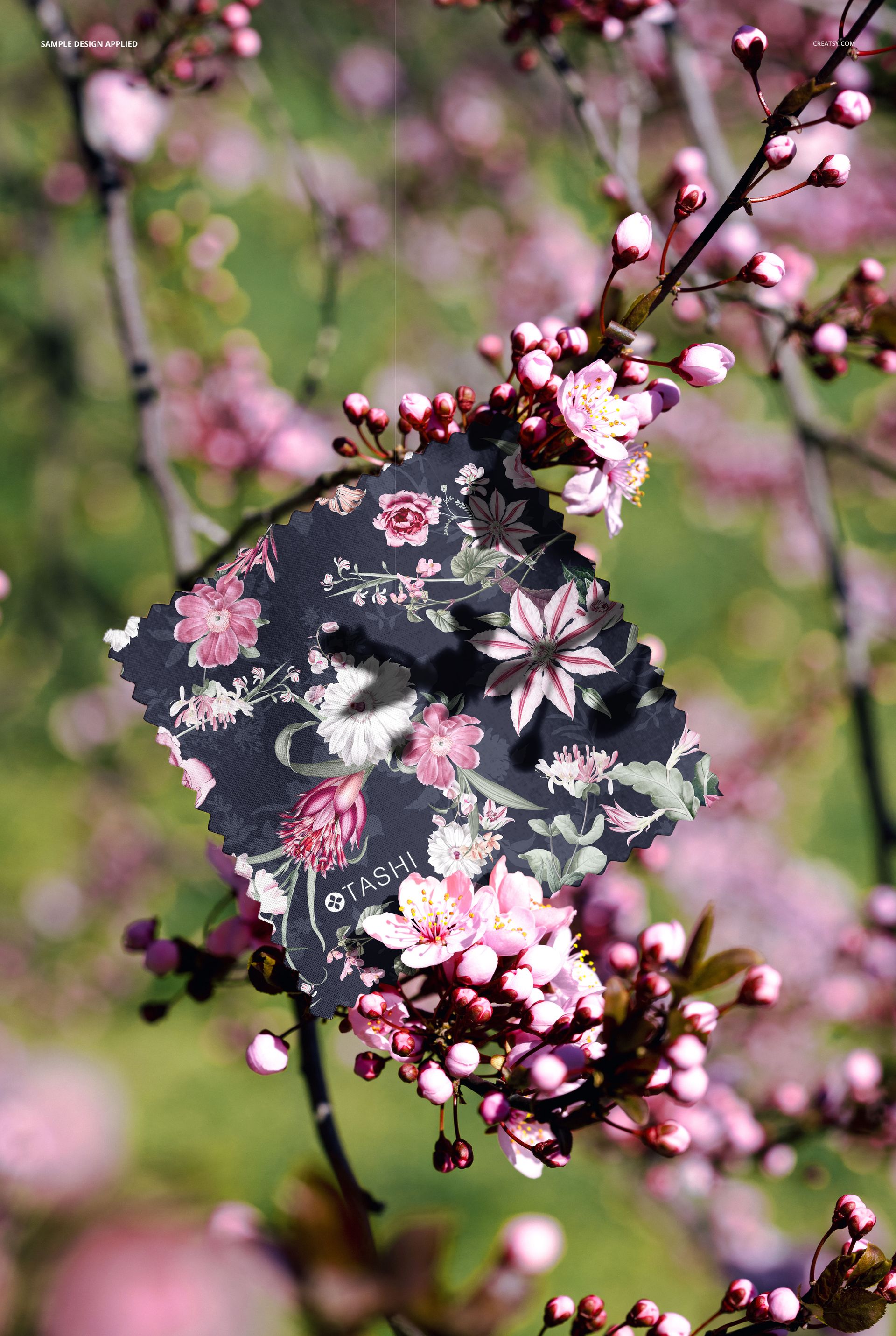 Mockup of a square fabric swatch featuring pink and white flowers, positioned among blooming cherry blossoms.