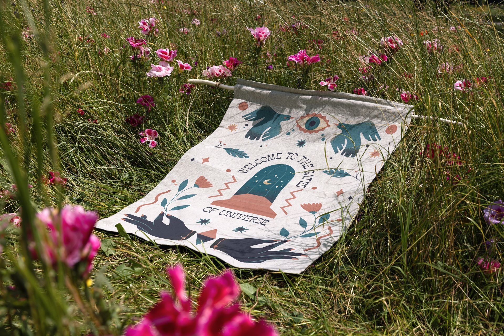 26x36 woven tapestry mockup featuring a playful graphic pattern displayed outdoors on grass with blooming flowers.