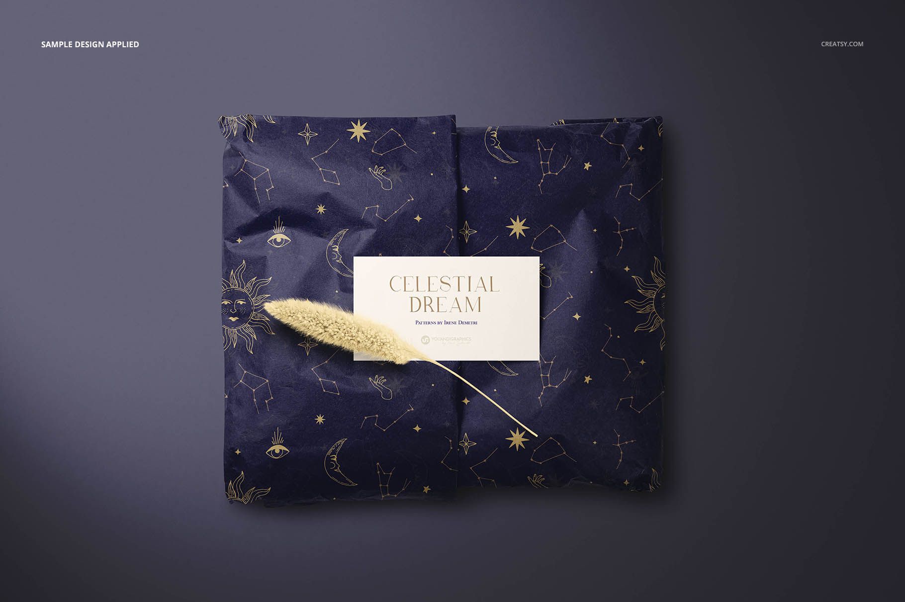 Dark blue gift wrapping tissue paper mockup with gold constellation designs and a rectangular white card in the center.