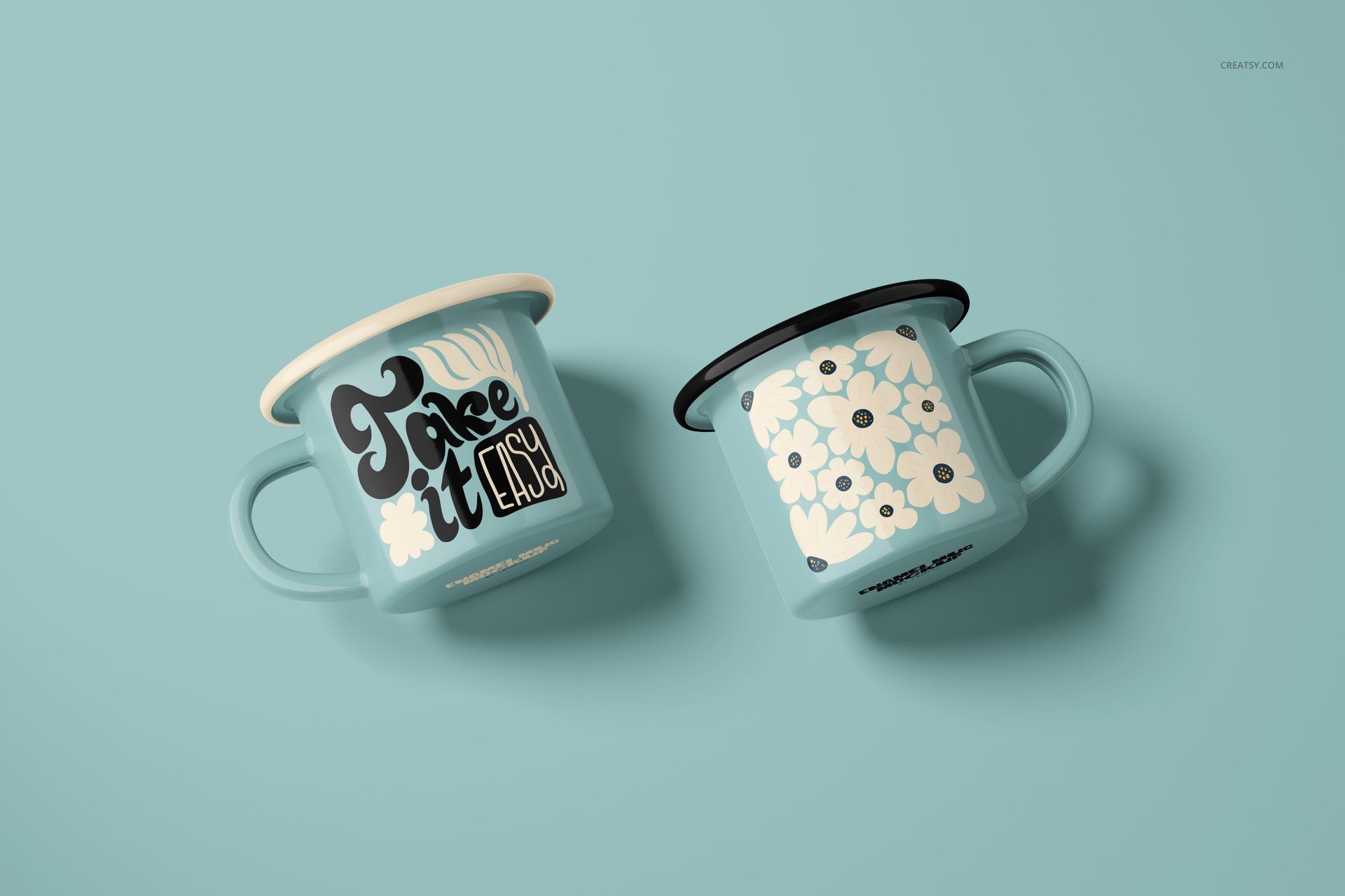 Two light blue enamel mugs with different designs, one featuring bold text and the other a floral pattern, shown on a solid blue surface.