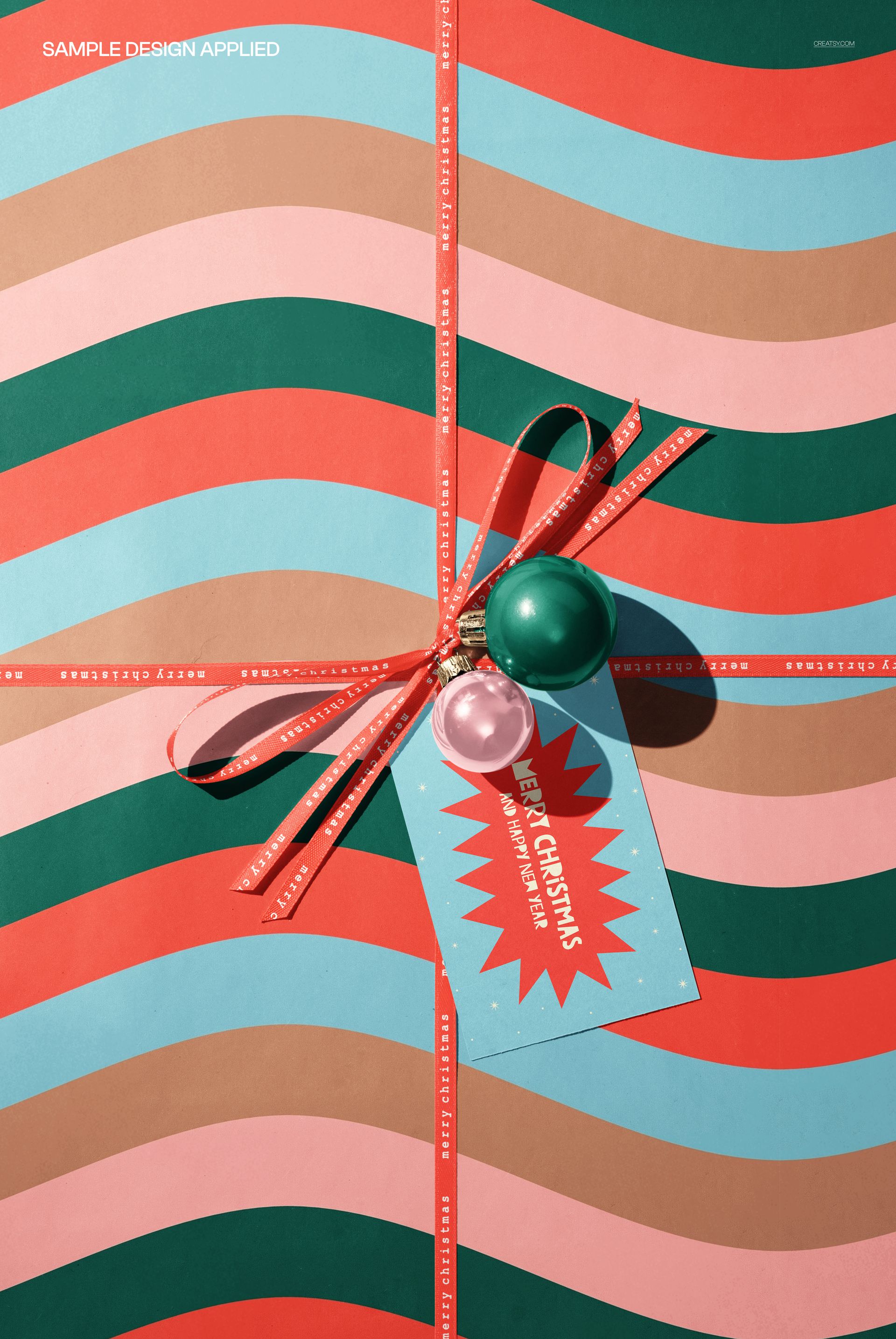 Christmas wrapping paper gift box mockup featuring wavy stripes in red, green, and beige, with ribbon and festive tag.