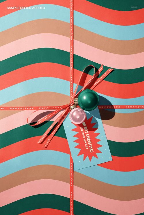 Christmas wrapping paper gift box mockup featuring wavy stripes in red, green, and beige, with ribbon and festive tag.