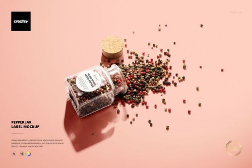Glass pepper jar with a round white label mockup, jar tipped over and peppercorns scattered on a light pink surface.